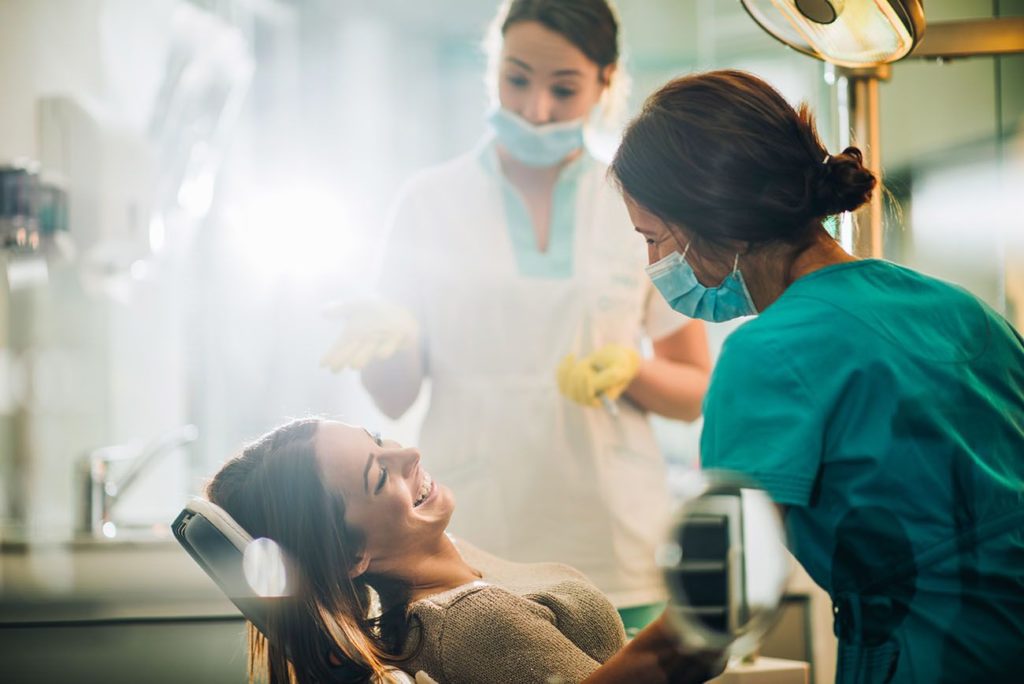 Smiling woman sitting in dentist chair and talking to her dentist before routine appointment teeth examination general dentistry dentist in Gaithersburg Maryland