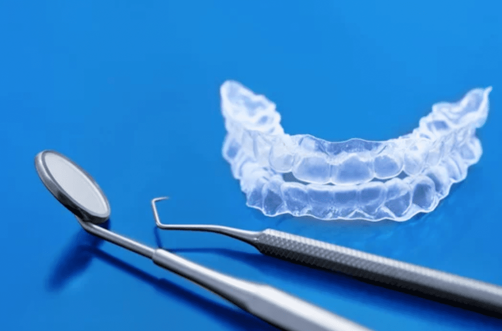 Set of clear Invisalign aligners on blue background with dental mirror and scaler cosmetic dentistry dentist in Gaithersburg Maryland